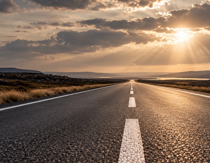 Gerade Landstraße, die im Abendlicht bis zum Horizont führt
